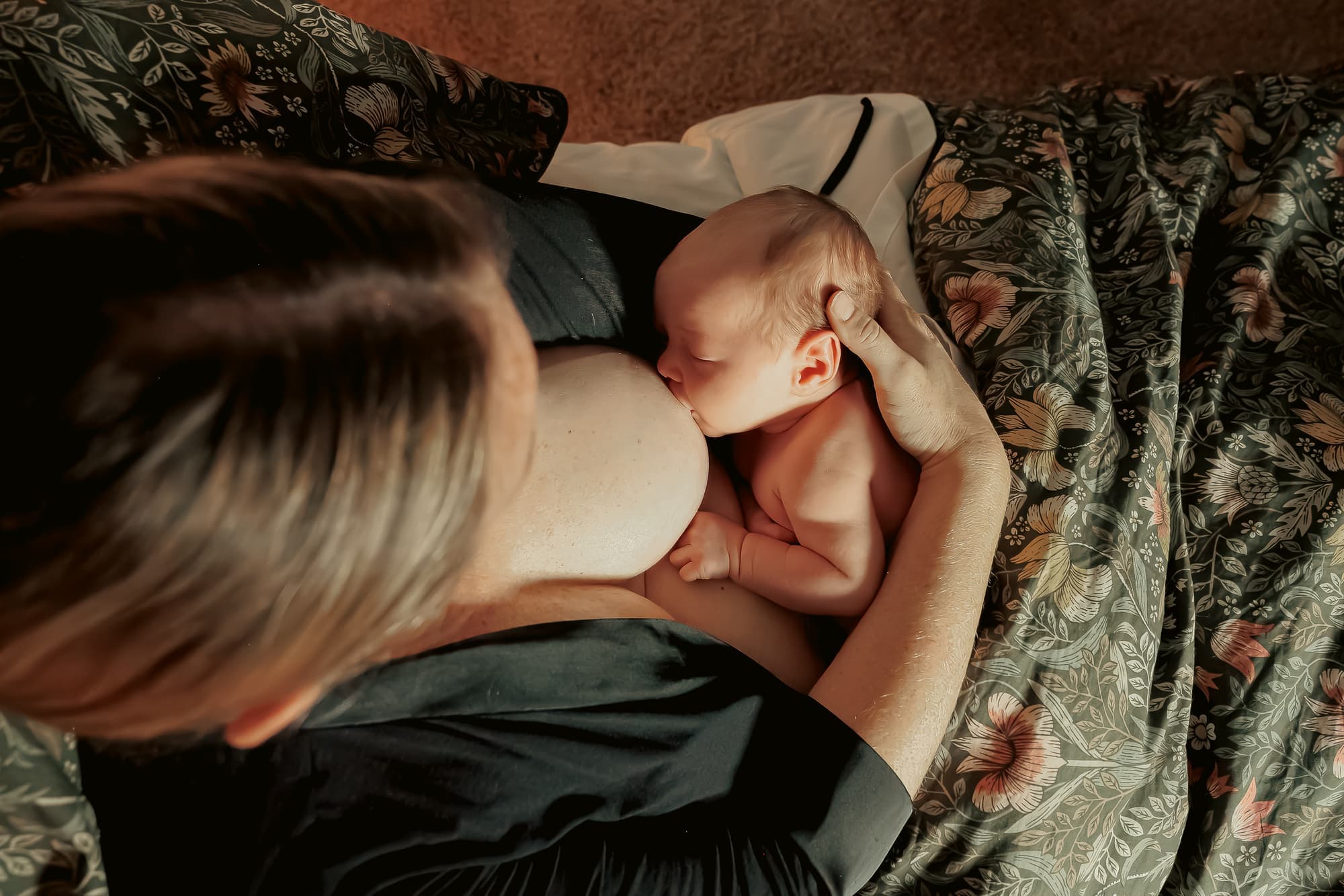 Overhead view of a mother nursing her sleeping newborn skin-to-skin