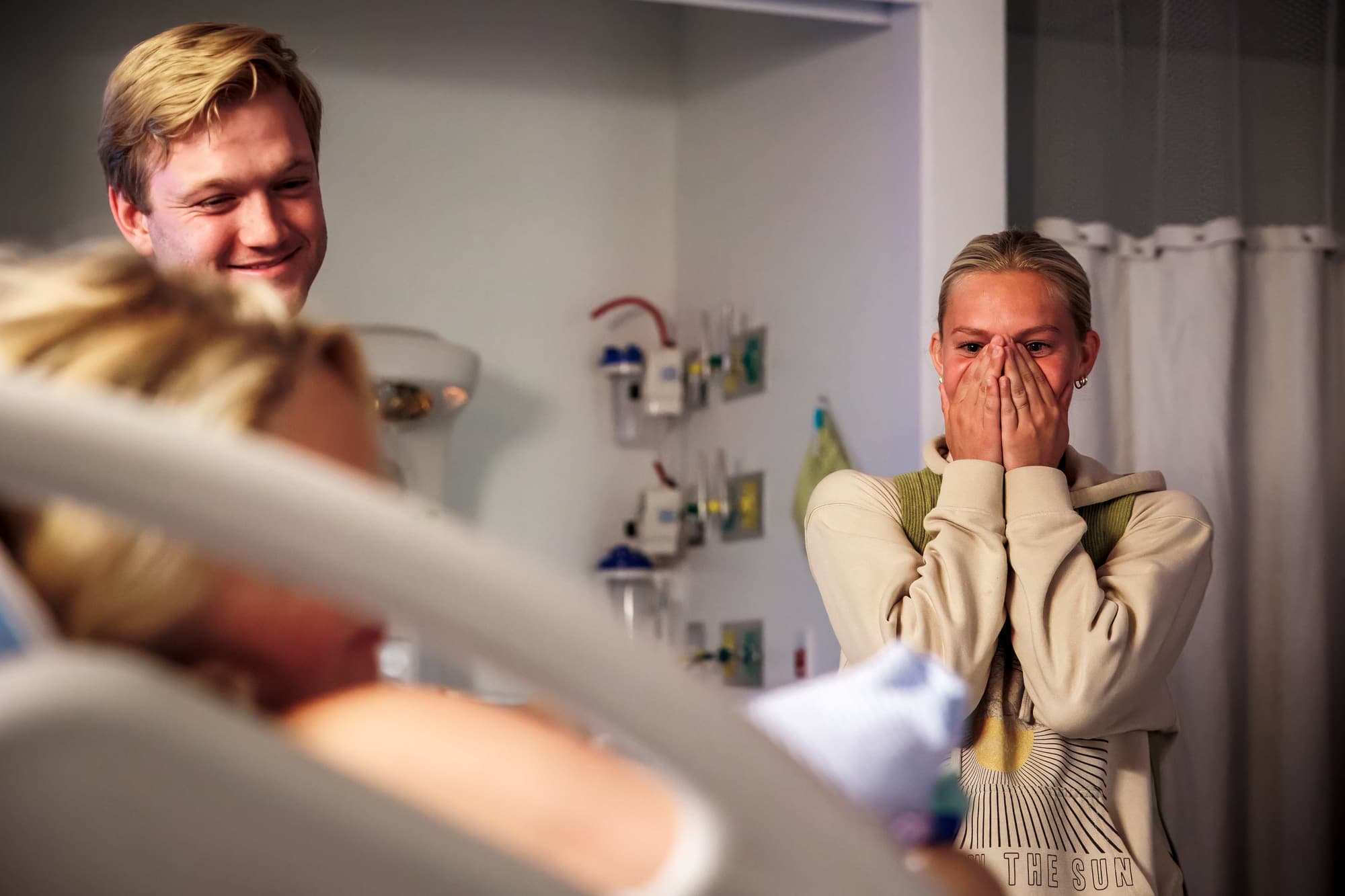 A grinning father and a partner overcome with joyful tears as the baby arrives