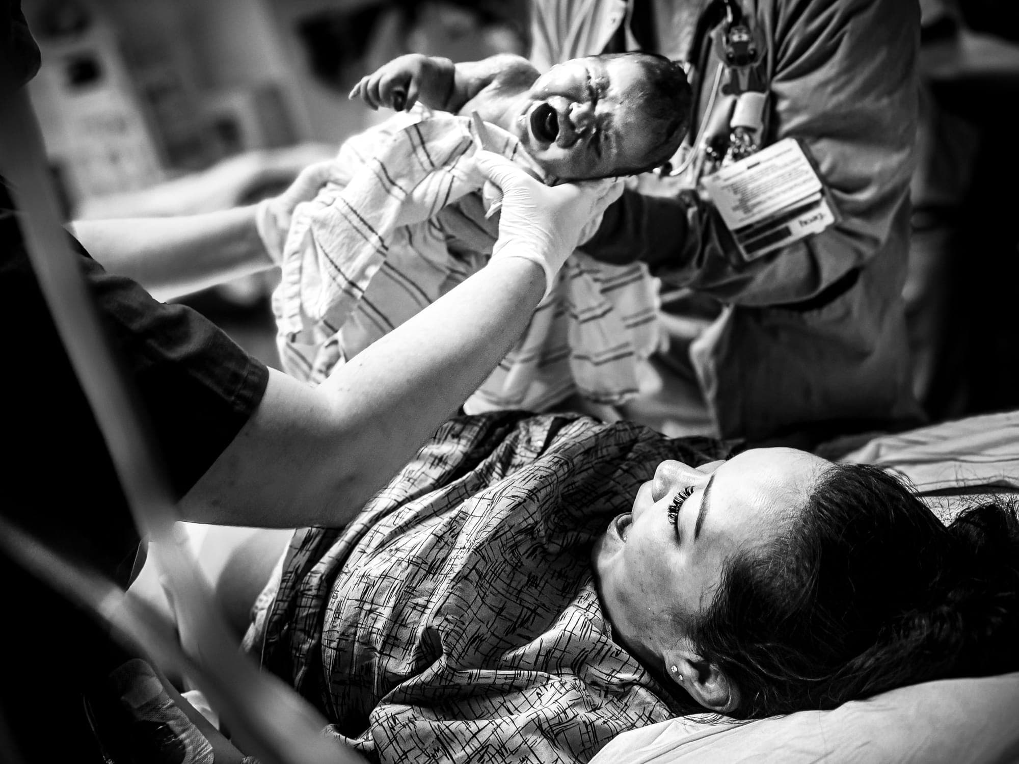 The moment of birth as the baby is lifted and the mother cries out in relief