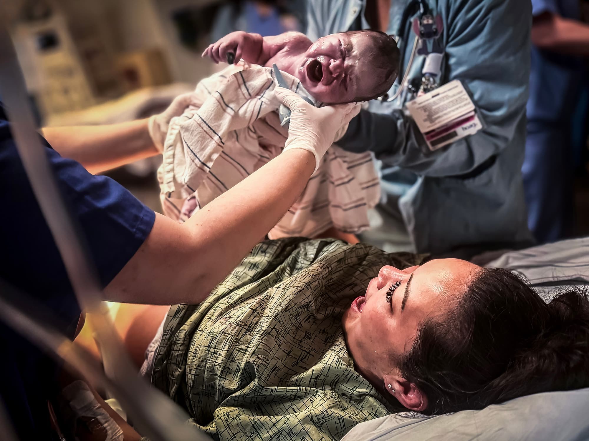 The moment of birth as the baby is lifted and the mother cries out in relief