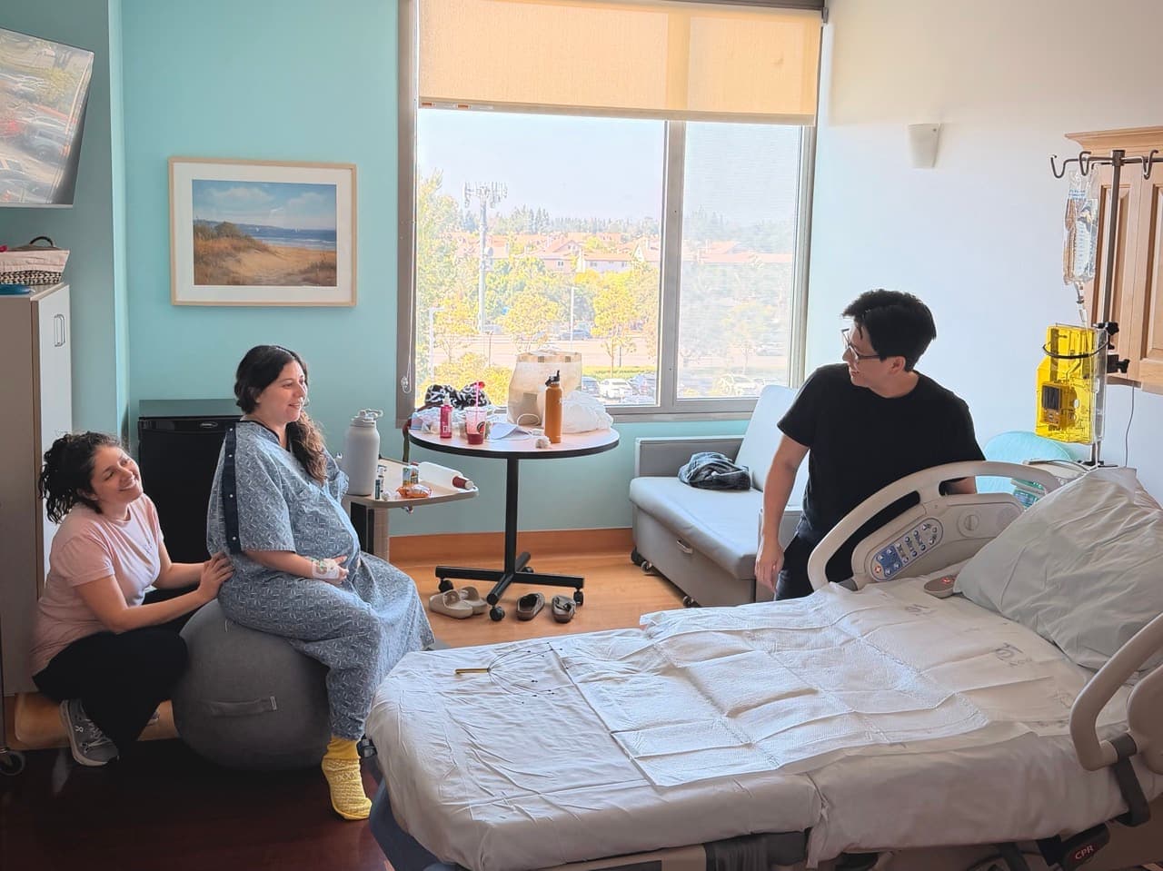 Maribel supporting a laboring mother on a birth ball while her partner stands nearby