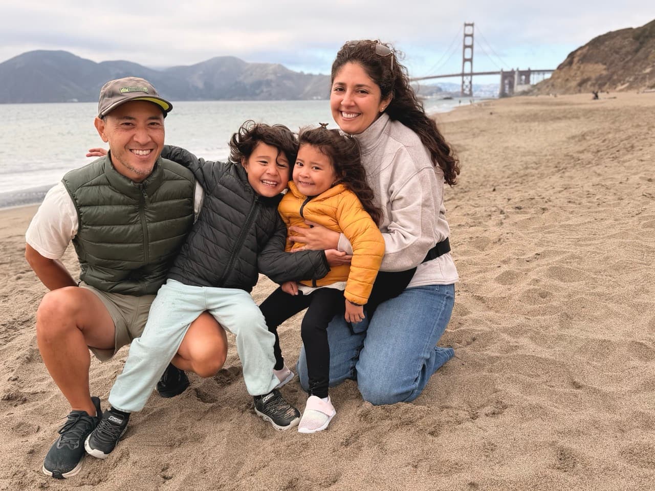 Maribel with her partner and two children on the beach, the Golden Gate Bridge behind them