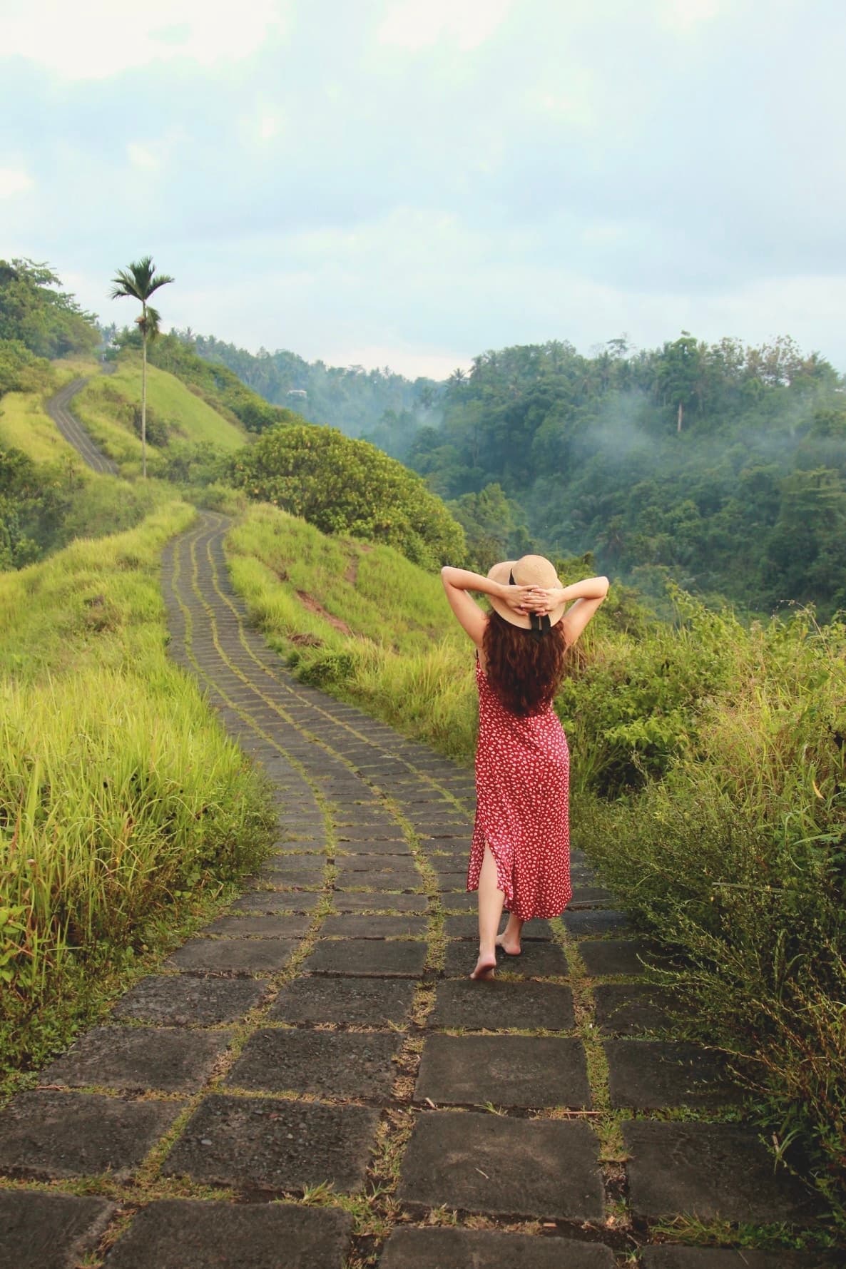 Maribel walking a stone path through lush green hills while traveling