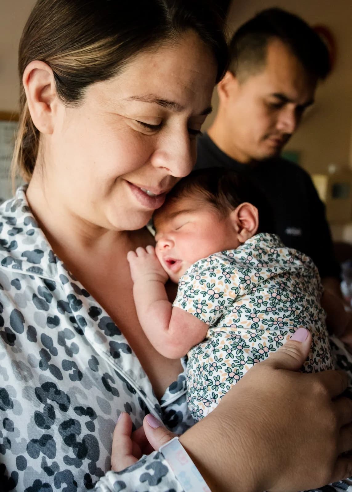 A newborn nursing and holding their mother's finger