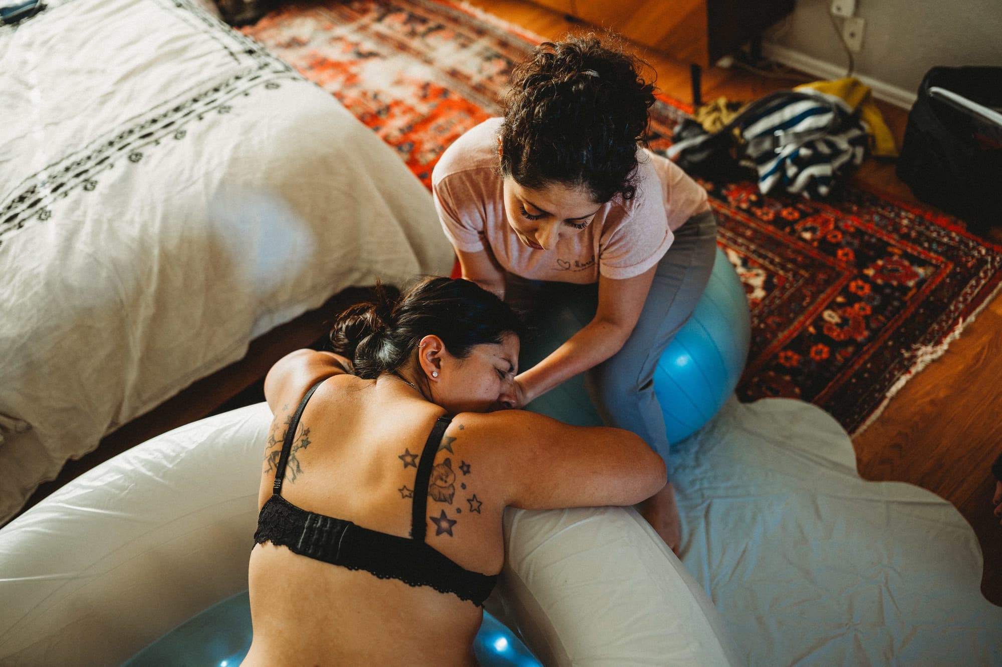 Maribel leaning in forehead-to-forehead to comfort a mother laboring at the edge of a birth pool at home