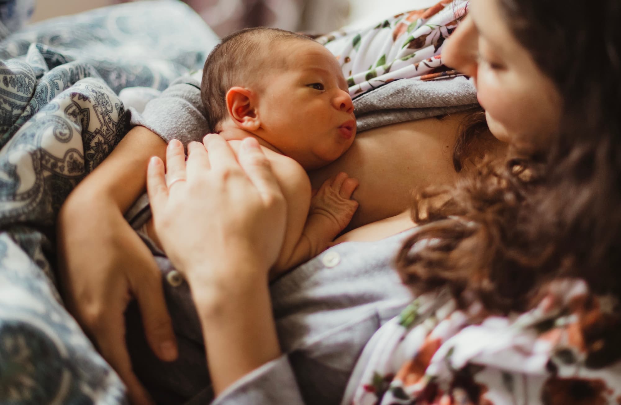 A newborn resting skin-to-skin on their mother's chest as she gazes down at them